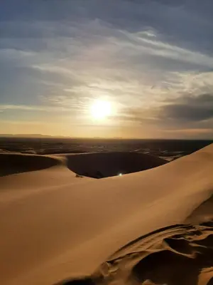 a sunset over the desert with the sun in the background at Riad Manaoui in Marrakech