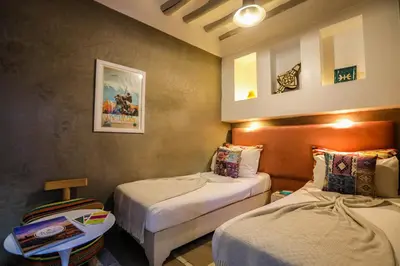 a hotel room with two beds and a table at Riad les 2 Portes in Marrakech