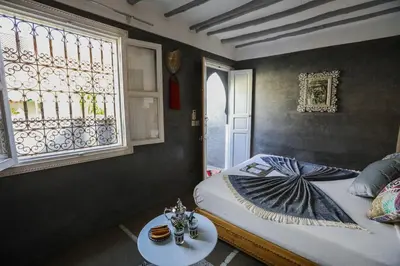 a bedroom with a bed with a table and a window at Riad les 2 Portes in Marrakech