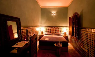 a bedroom with a bed and a mirror and a table at Riad Lakhdar in Marrakech