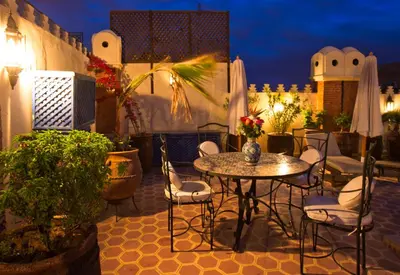 a table and chairs on a patio at night at Riad Lakhdar in Marrakech