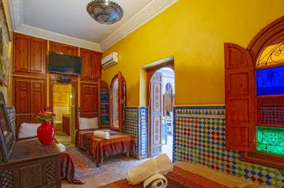 a yellow room with a bed and a window at Riad Lakhdar in Marrakech