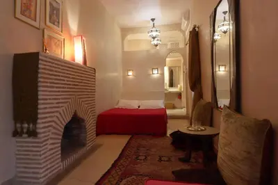 a living room with a fireplace and a red bed at Dar Warda in Marrakech