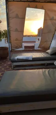 two beds on a roof with the sunset in the background at Dar Warda in Marrakech
