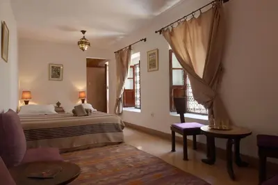 a bedroom with a bed and a chair and a window at Dar Warda in Marrakech