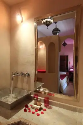 a bathroom with a mirror and a sink with roses on the floor at Dar Warda in Marrakech