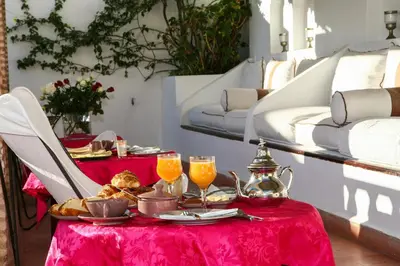 a table with a red table cloth with food and drinks at Dar Warda in Marrakech