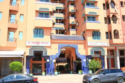 a tall building with cars parked in front of it at El Hamra Hotel in Marrakech