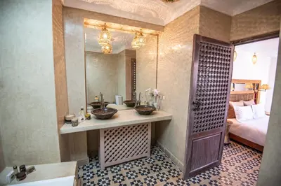 a bathroom with a sink and a mirror and a bed at Riad Dar Tmania in Marrakech