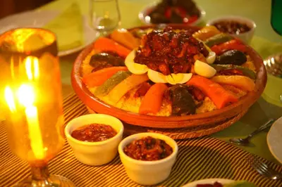 a table with a bowl of vegetables and a candle at Riad Arbre Bleu in Marrakech