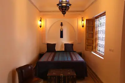 a bedroom with a bed and a chair and a window at Riad Arbre Bleu in Marrakech