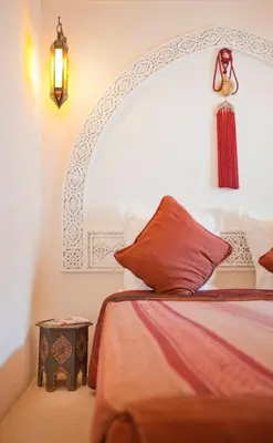 a bedroom with a bed with an arched headboard at Riad Arbre Bleu in Marrakech