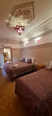 a hotel room with two beds and a chandelier at Riad Arbre Bleu in Marrakech