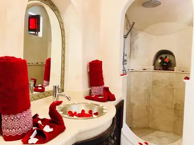a bathroom with red towels and a sink and a shower at Riad AKL in Marrakech