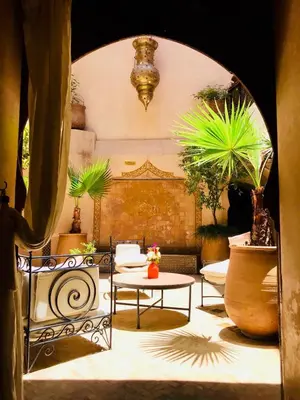 a room with a table and chairs and plants at Riad AKL in Marrakech