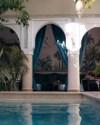 a swimming pool in a house with a blue curtain at Riad Rafaele & SPA in Marrakech