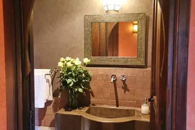a bathroom with a sink with a vase of flowers at Riad Marrakiss in Marrakech