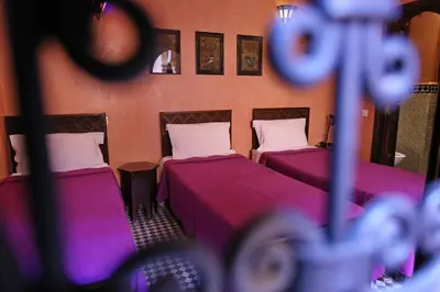 two beds in a room with purple sheets at Riad Marrakiss in Marrakech