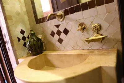 a bathroom with a sink with a vase and a mirror at Riad Marrakiss in Marrakech