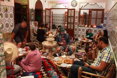 a group of people sitting at tables in a restaurant at Mosaic Hostel in Marrakech