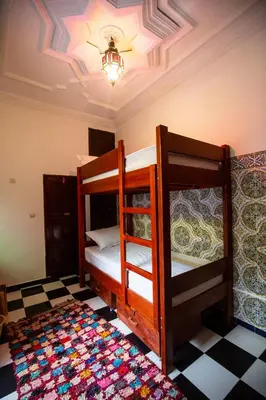 two bunk beds in a room with a checkered floor at Mosaic Hostel in Marrakech