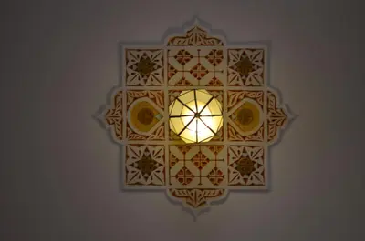a chandelier with a yellow light on a wall at Mosaic Hostel in Marrakech