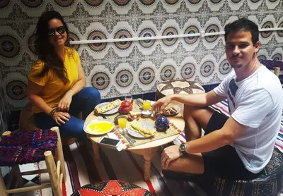 a man and woman sitting at a table with a plate of food at Mosaic Hostel in Marrakech