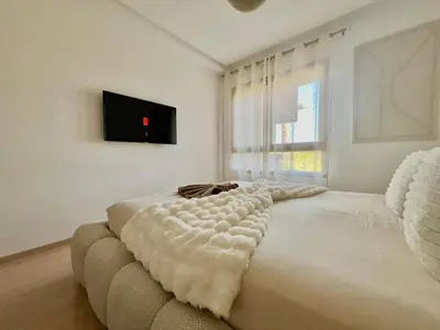 a white bedroom with a couch and a tv at Marrakech golf City prestigia in Marrakech