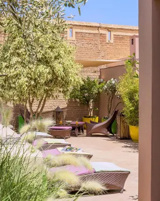 a courtyard with chairs and tables and trees at Riad Idra in Marrakech