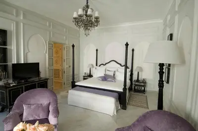 a bedroom with a bed and a tv and two chairs at Riad Idra in Marrakech