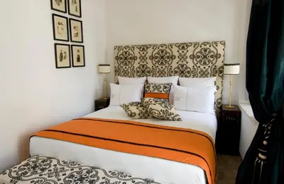 a bedroom with a large bed with an orange and white blanket at Riad Idra in Marrakech