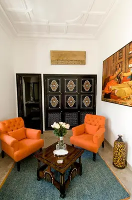 a living room with two orange chairs and a coffee table at Riad Idra in Marrakech