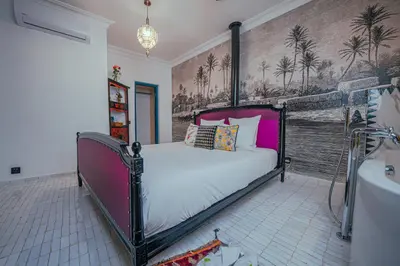 a bedroom with a bed and a wall with palm trees at Riad Tibibt in Marrakech