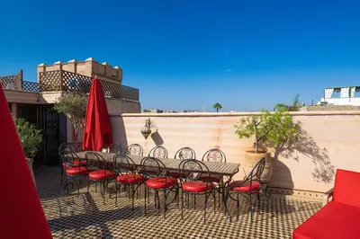 a group of tables and chairs with red umbrellas at Maison Do in Marrakech