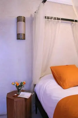 a bedroom with a bed and a vase of flowers on a table at Riad CHERRATA in Marrakech