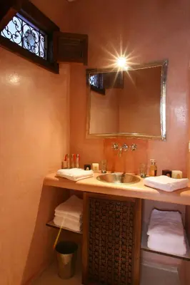 a bathroom with a sink and a mirror and towels at Riad CHERRATA in Marrakech