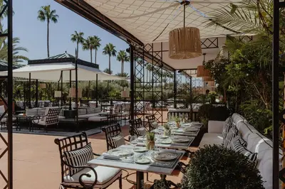a patio with a table and chairs and palm trees at Selman Marrakech in Marrakech