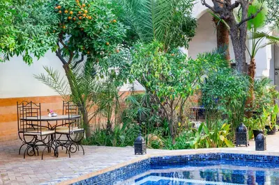 a table and chairs next to a swimming pool at Riad Laila in Marrakech
