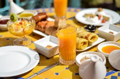 a table with plates of food and a glass of orange juice at Riad Ben Tachfine in Marrakech
