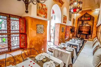 a restaurant with tables and chairs and windows at Riad Chorfa in Marrakech