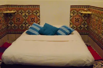 a bed with blue and white pillows on it at Riad Dar Mchicha in Marrakech