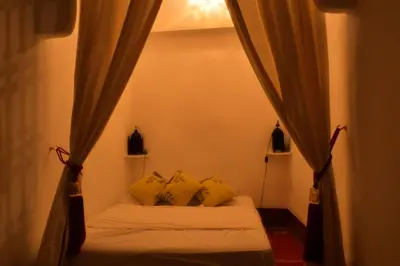 a bedroom with a bed with yellow pillows and curtains at Riad Dar Mchicha in Marrakech