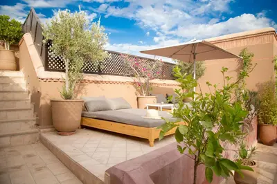 a patio with a bench and an umbrella at Riad Olema et Spa in Marrakech