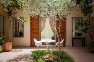 a table and chairs in a courtyard with trees at Riad Olema et Spa in Marrakech