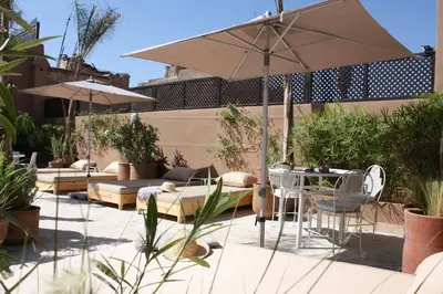 a patio with a table and chairs and an umbrella at Riad Olema et Spa in Marrakech