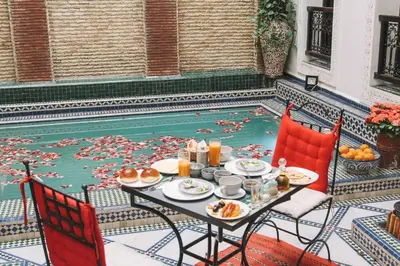 a table with food next to a swimming pool at Riad Tamarrakecht in Marrakech