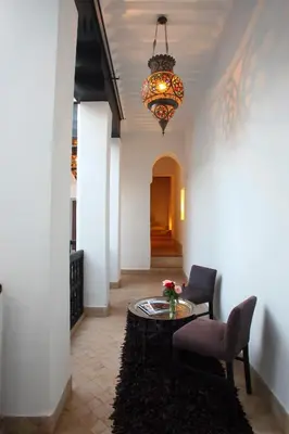a hallway with a table and a chair and a chandelier at Riad Dar Asam in Marrakech