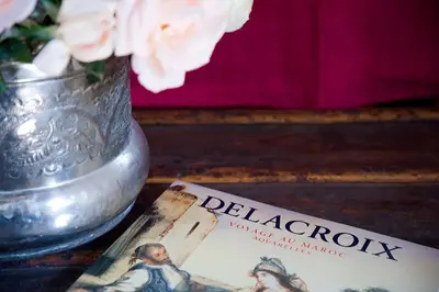 a book on a table next to a vase with flowers at Riad Le J in Marrakech