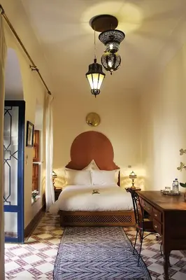 a bedroom with a large bed and a desk and a table at Riad Soundouss in Marrakech