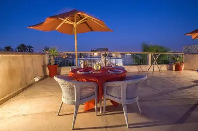 a table with chairs and an umbrella on a patio at Riad Charaï in Marrakech